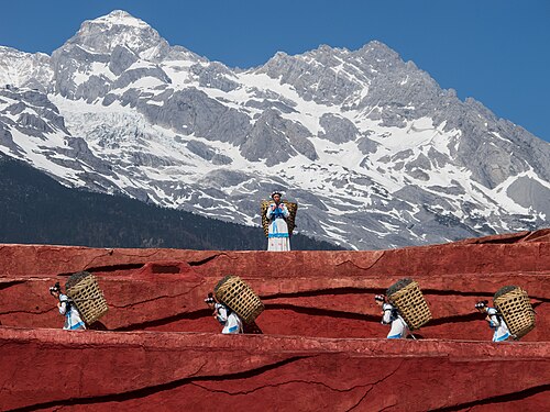 Performers carrying baskets before Jade Dragon Snow Mountain